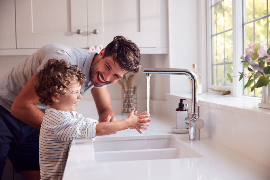 homeowner at kitchen sink with running water