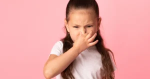 A young girl covering her nose with a concerned expression, illustrating a house with an unpleasant sewage smell.